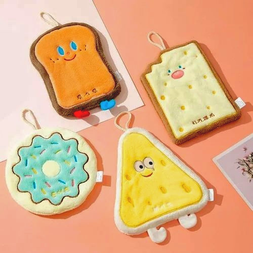 Four cute plush toys shaped like toast, donut, and triangle with cartoon faces on a pink background.