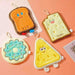 Four cute plush toys shaped like toast, donut, and triangle with cartoon faces on a pink background.